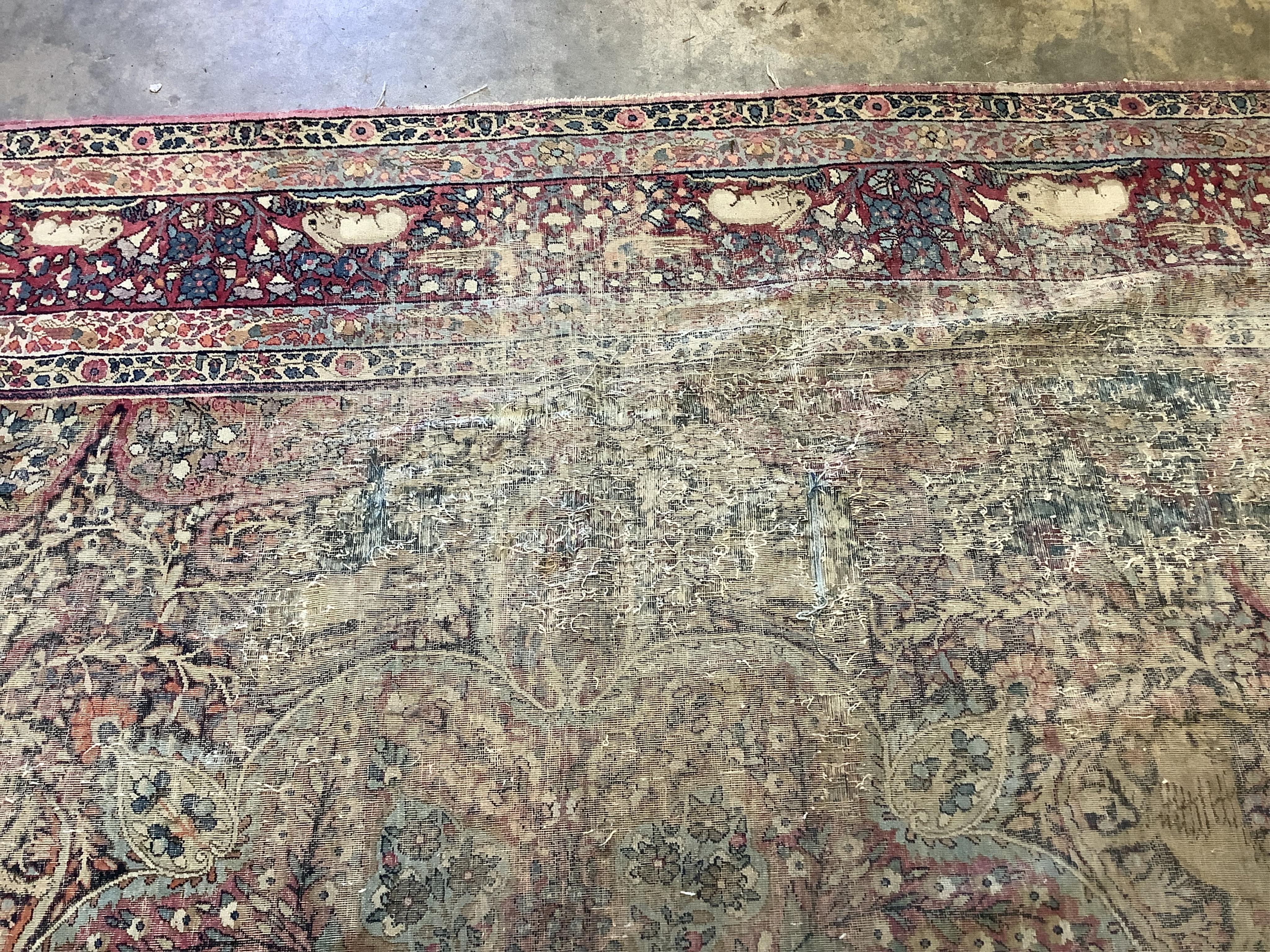 An antique Kirman ivory ground pictorial carpet (severely worn), 348 x 265cm
